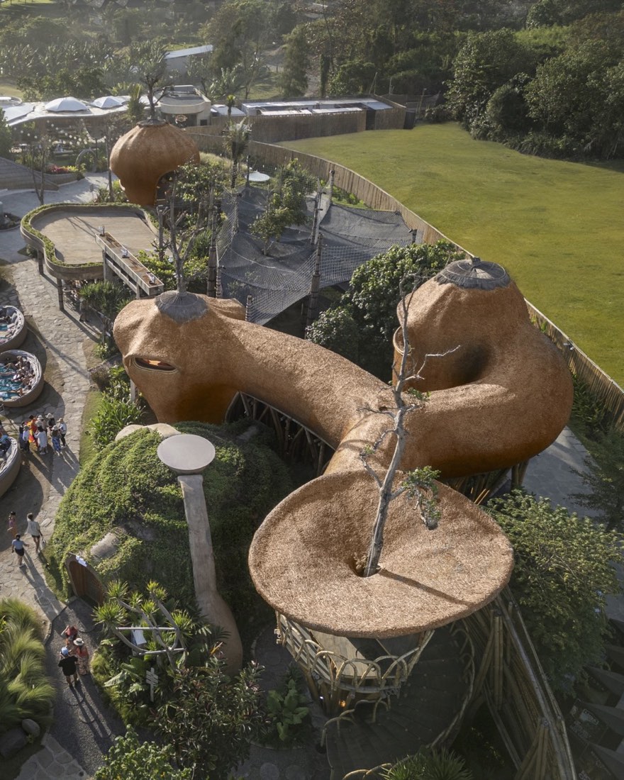 Aerial of the earthen thatched tree-pod structures and net platforms in the garden zone at Nuanu Creative City, beside Luna Beach Club